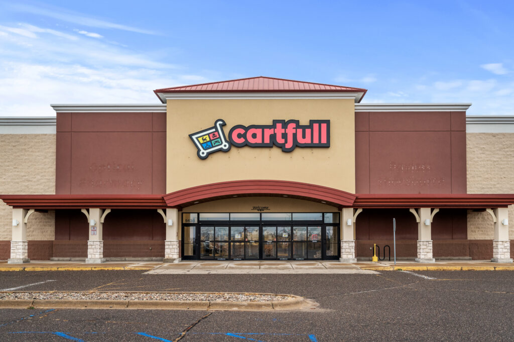 Exterior view of a Cartfull retail store building with a red and tan facade under a clear blue sky.